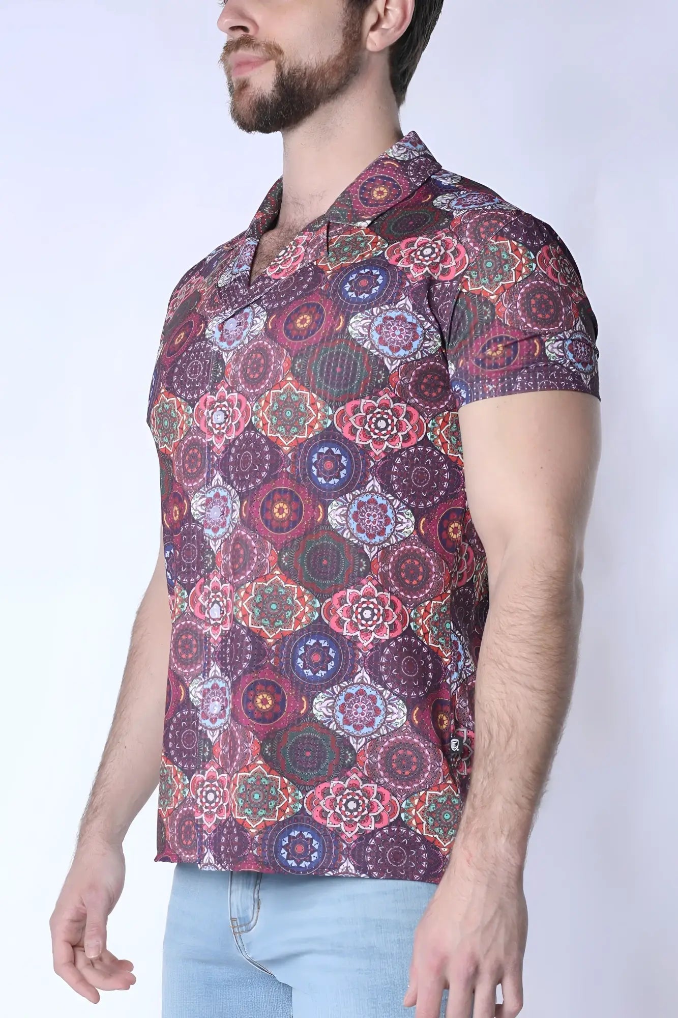 A man wearing a balboa button down shirt with a short-sleeved multicolored mandala pattern in purple pink and green