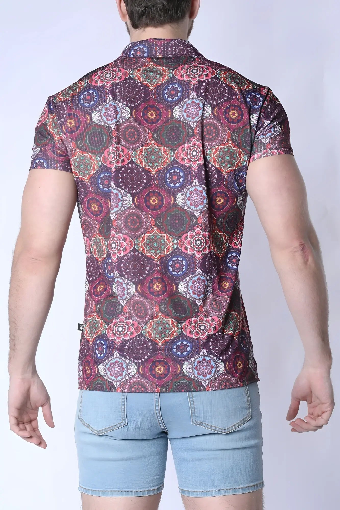 A man wearing a balboa button down shirt with colorful mandala patterns on a dark maroon background