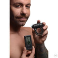A man holds the black silicone Bang 25X vibrating cock ring and its matching digital remote control.
