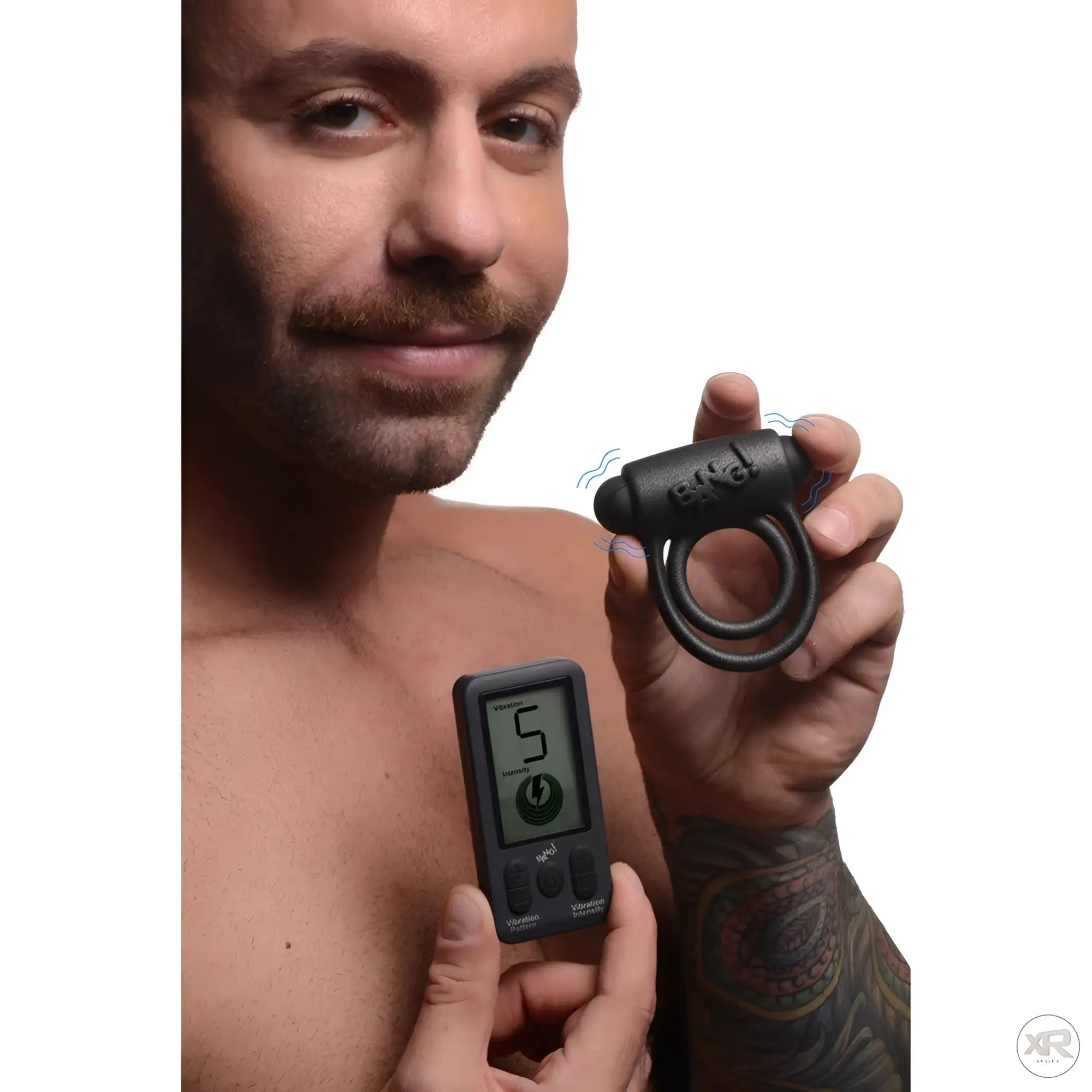 A man holds the black silicone Bang 25X vibrating cock ring and its matching digital remote control.