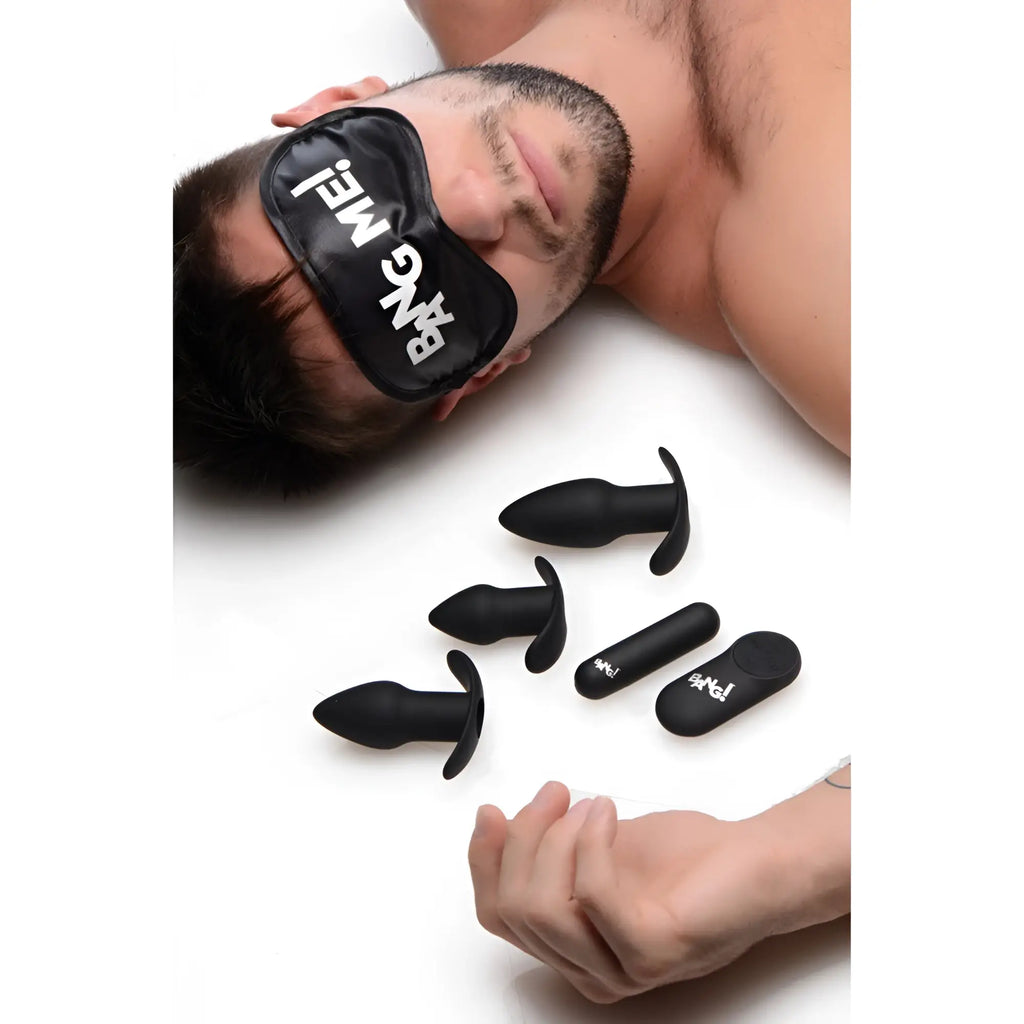 Bang Backdoor Adventure 3-piece black silicone plug kit with remote, shown near a man wearing a "BANG ME!" sleep mask.