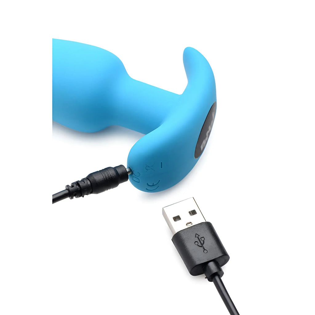 Bright blue Bang 21X vibrating silicone butt plug being charged with a black USB cable against a white background.