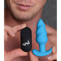 A person holds a blue silicone swirl butt plug and a black Bang remote control.