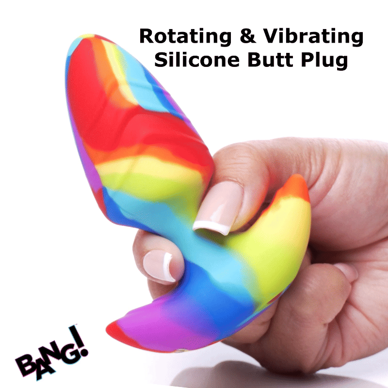 A hand holds a colorful, swirled rainbow silicone Bang rotating and vibrating butt plug against a white background.