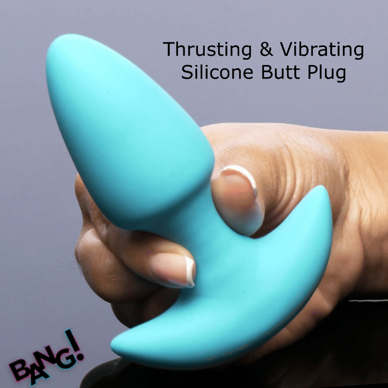 Hand holding a turquoise, silicone Bang Thrusting & Vibrating Butt Plug with a T-shaped base against a gray background.