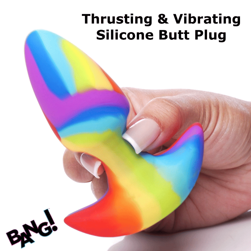 A hand holds a colorful, swirled rainbow silicone Bang thrusting and vibrating butt plug against a white background.