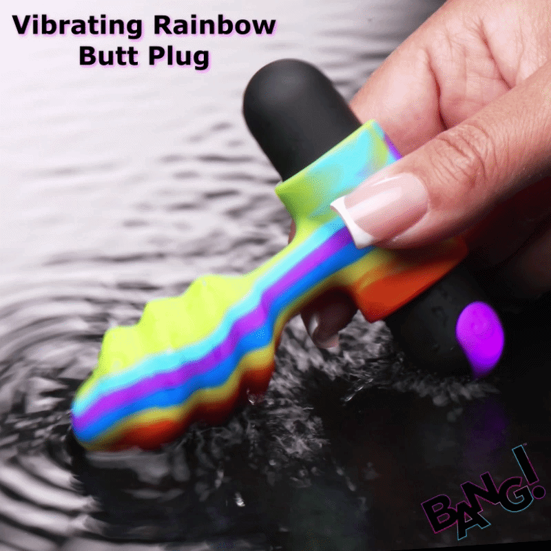Bang Vibrating Rainbow Butt Plug with a textured, colorful silicone handle being held over rippling water.