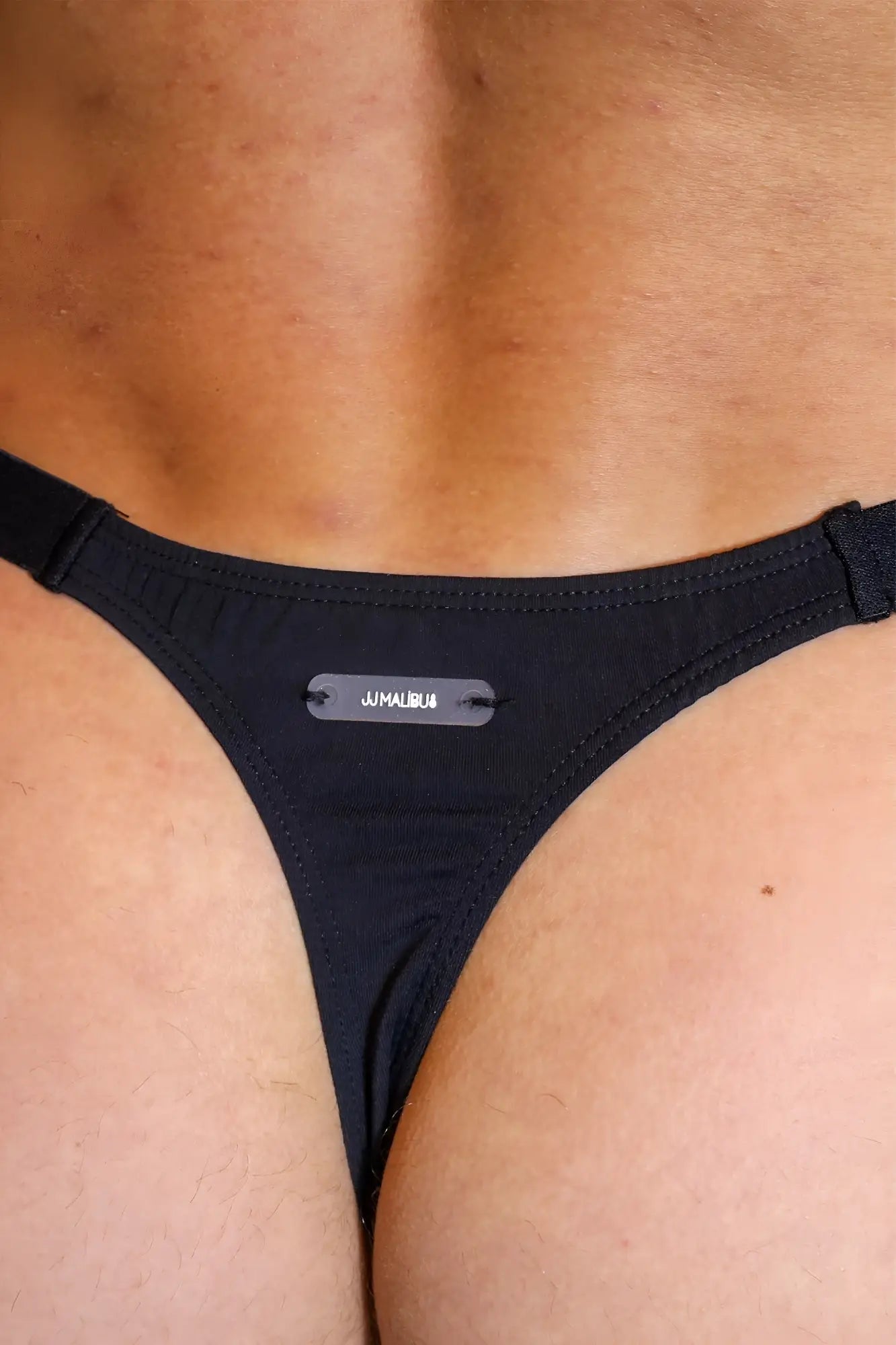 Black jmalibu barely there modal thong with sleek minimalist design and small metallic tag at center front