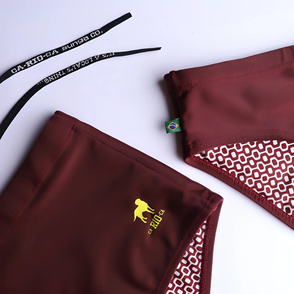 Maroon barolo burgundy solids mens swimming sunga with geometric patterned lining and yellow dog logo on the side