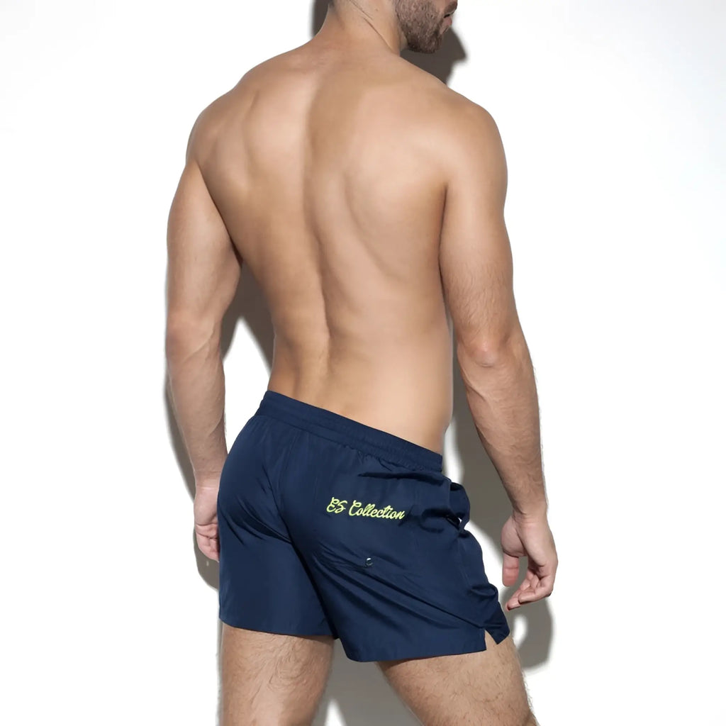 Navy blue basic boardshort back side with subtle yellow embroidered logo on the back pocket for athletic use