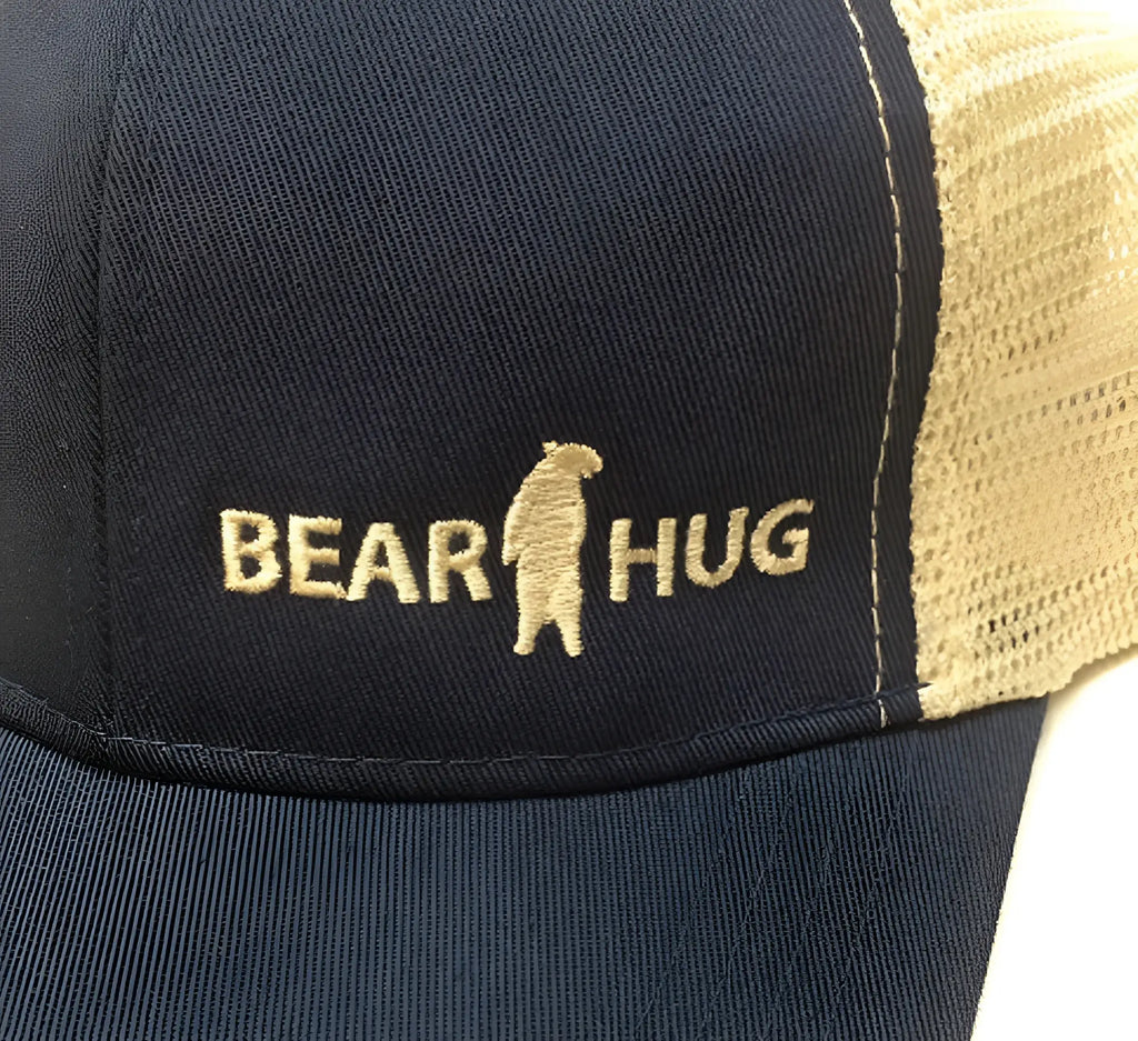 Navy blue and tan trucker baseball cap with embroidered gold bear hug logo perfect for casual wear