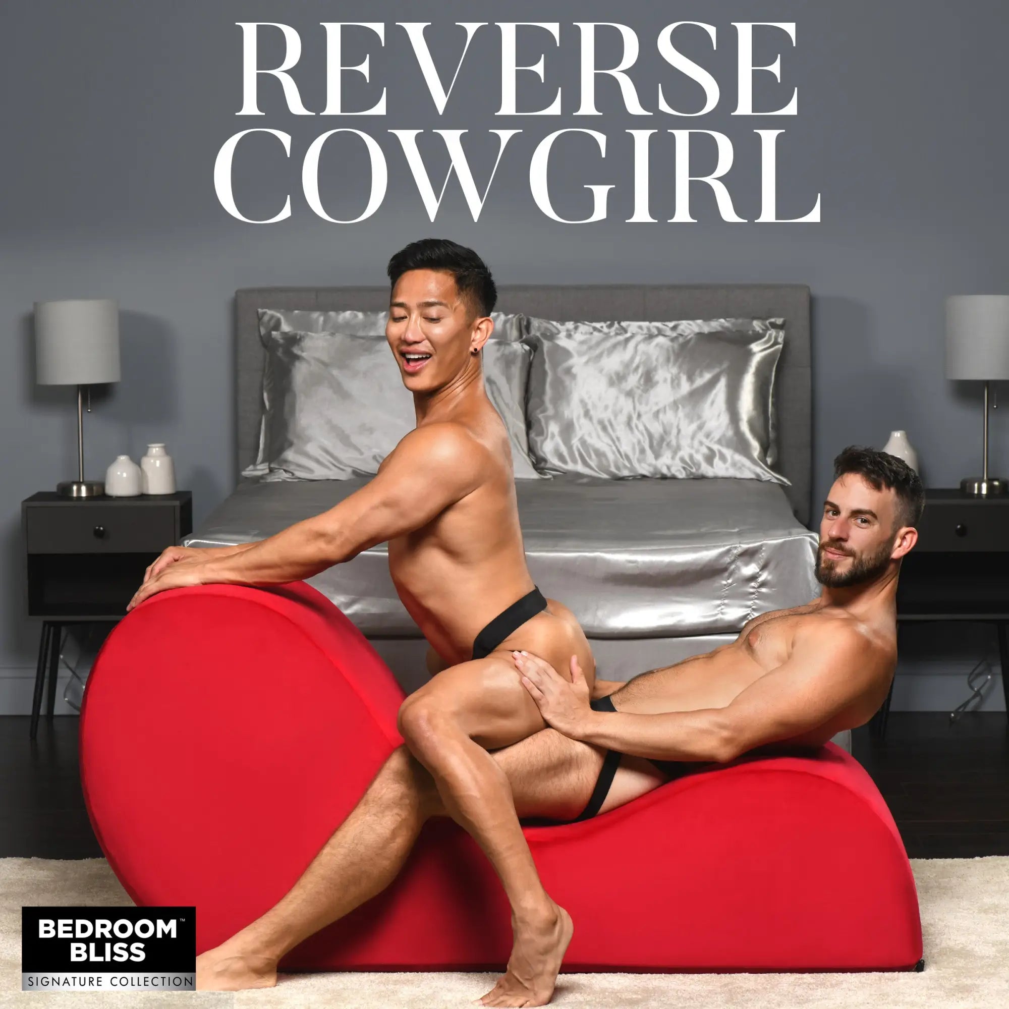 Two men in black underwear sit on a vibrant red, curved Bedroom Bliss The Love Couch in a modern bedroom.