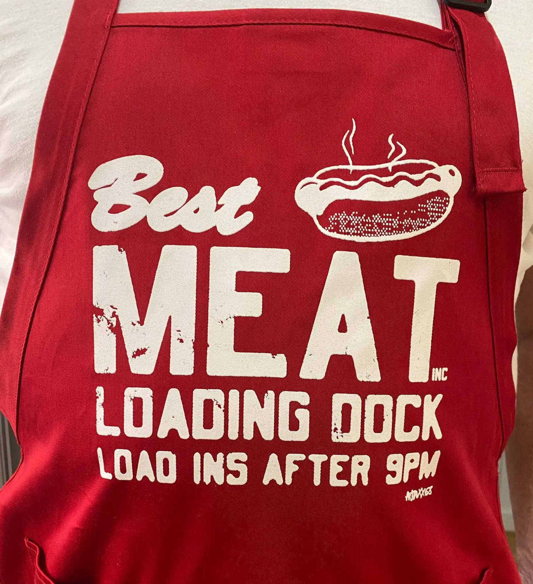 Red canvas meat apron with white distressed lettering and hot dog graphic for grilling and cooking use