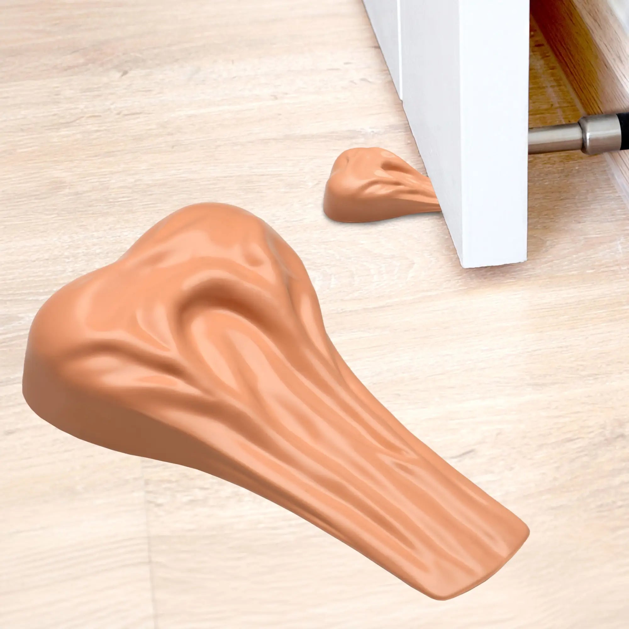 Big Ballers Big Balls door stop: tan, flesh-toned silicone wedge shaped like a scrotum, holding a white door open.
