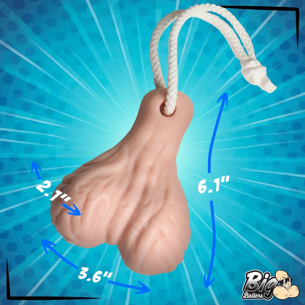 Big Ballers Balls Soap: A light-pink, scrotum-shaped bar of soap on a white rope with dimension arrows for scale.