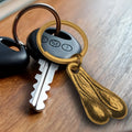 Big Ballers Brass Nuts keychain featuring a textured, gold-colored scrotum-shaped pendant attached to a metal keyring.