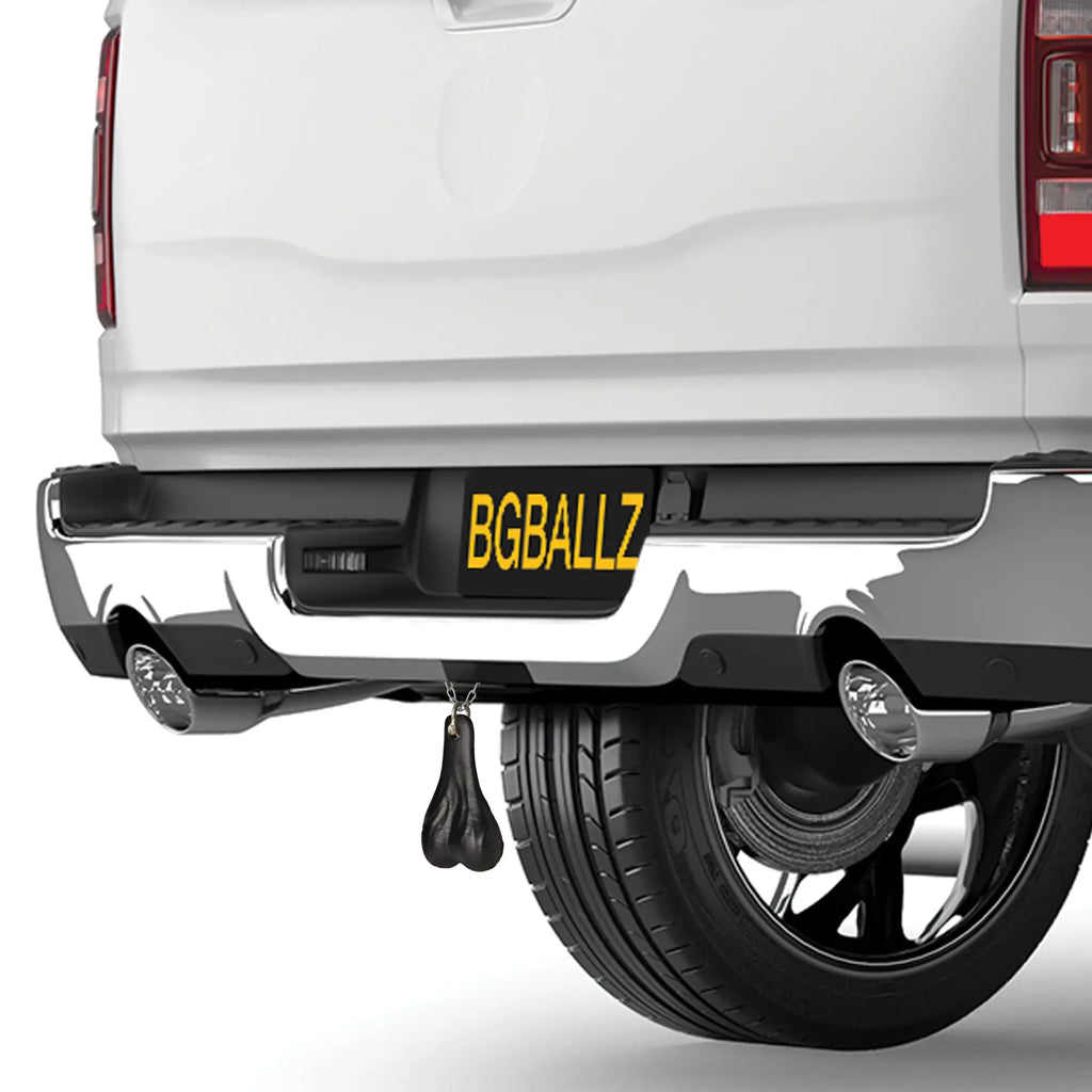 Big Ballers Truck Nuts in matte black hanging from the rear bumper of a white pickup truck.