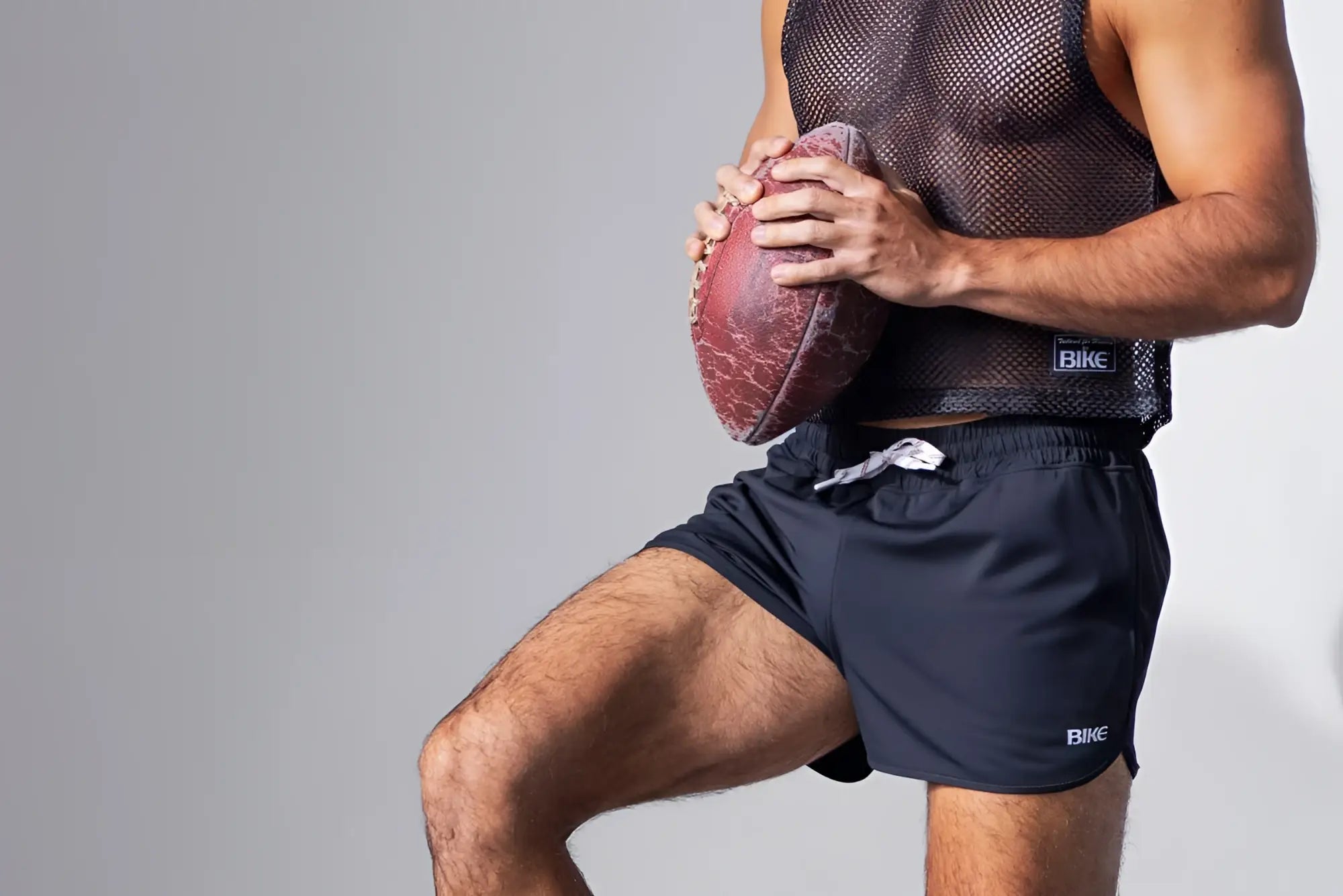 A worn reddish-brown american football shown with the bike athletic bam135 sleeveless black mesh practice jersey