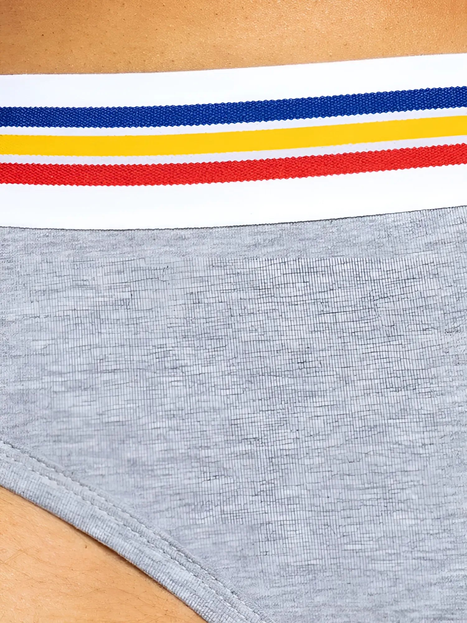 Gray heathered stretch cotton brief with white elastic waistband and blue yellow red stripes for athletic use