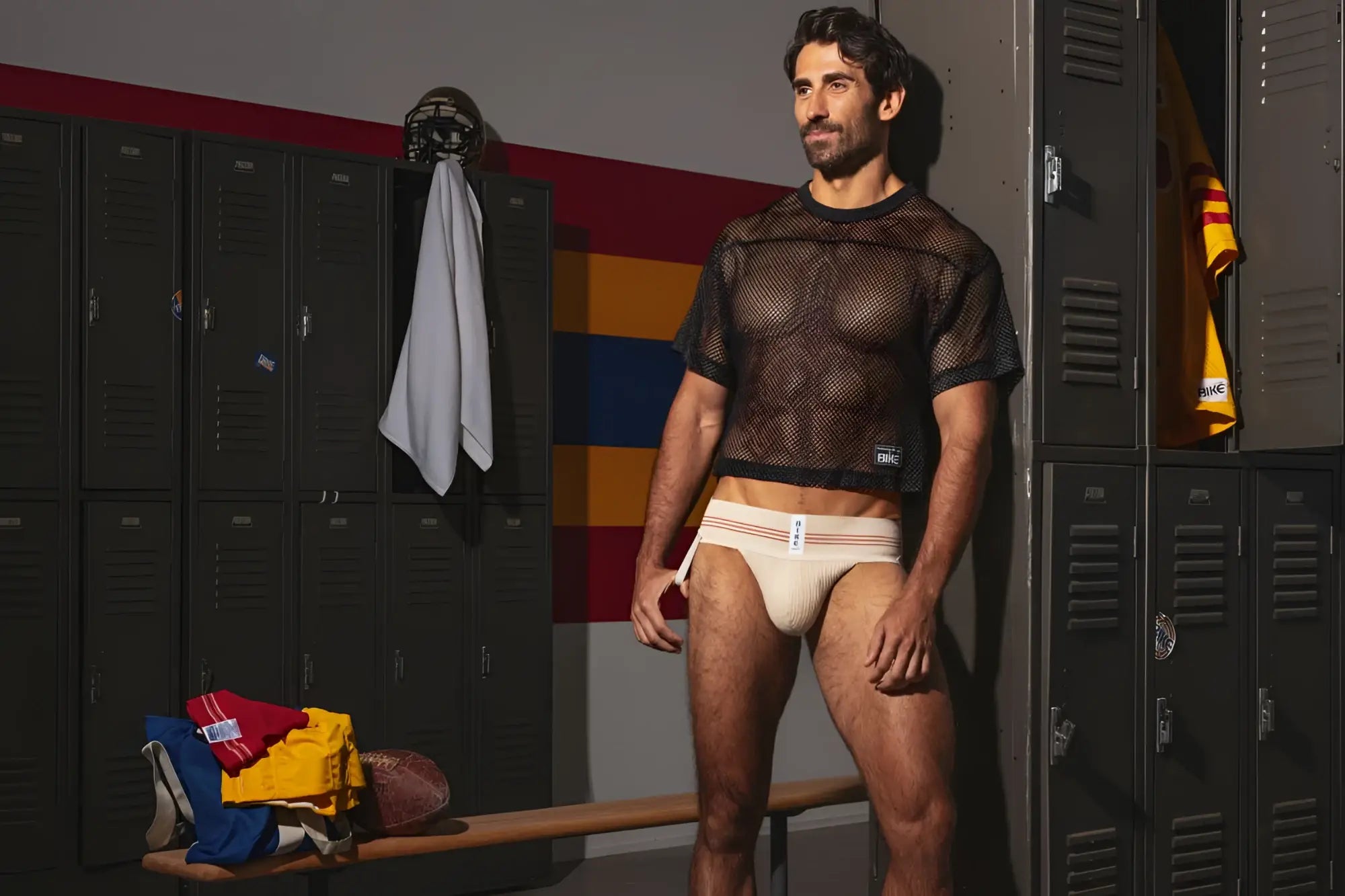 The man wears a black mesh short-sleeved top and beige BIKE Athletic BAS333 classic retro 1980s jockstrap in vintage cream