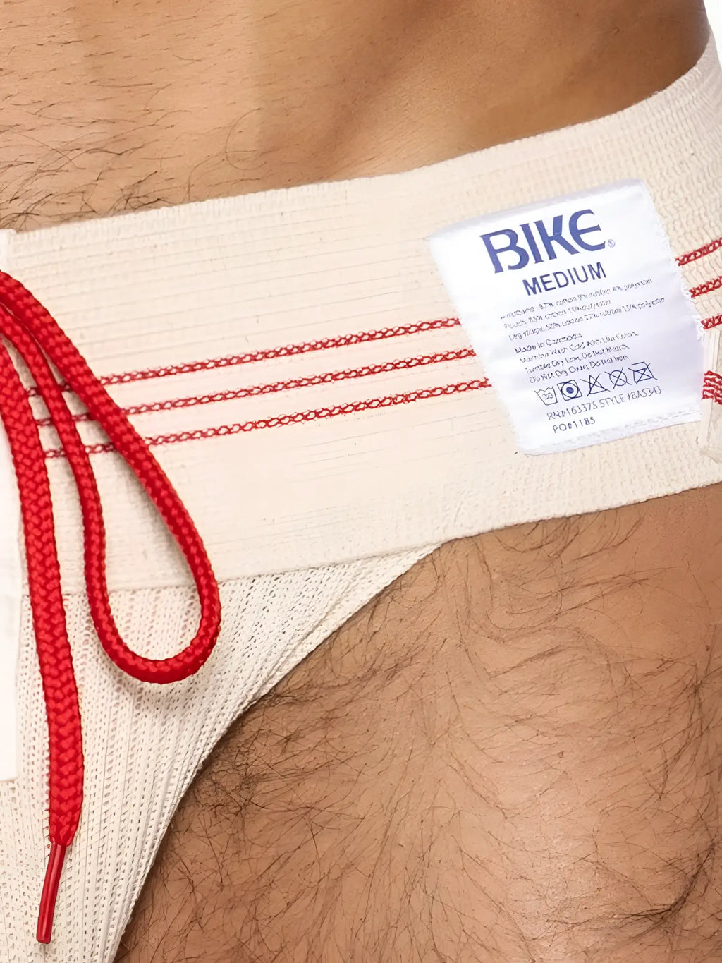 Beige bike brand swim trunks with red drawstring and trim matched with vintage cream bike athletic lace-up jockstrap