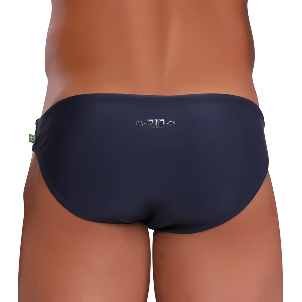 Navy blue bikini cut sunga swim trunks with silver ca-rio-24 embroidery and small Brazilian flag tag on side seam