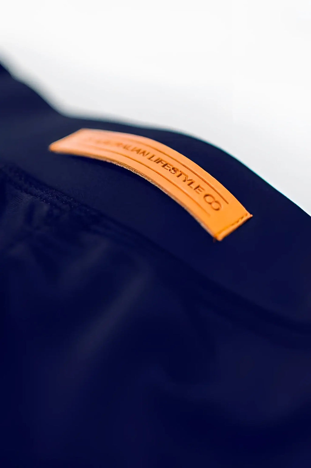 A tan leather patch embossed with lifestyle co on dark navy fabric on the back of bondi short