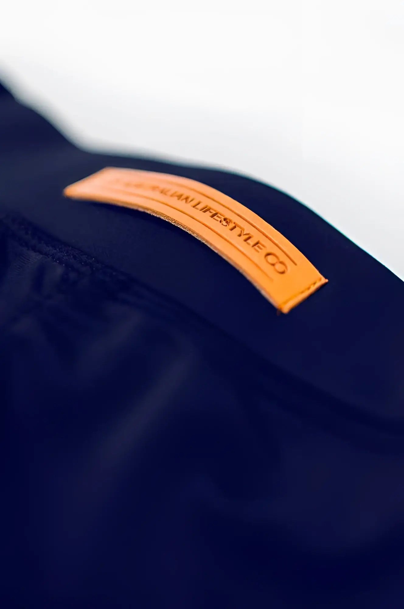 A tan leather patch embossed with lifestyle co on dark navy fabric on the back of bondi short