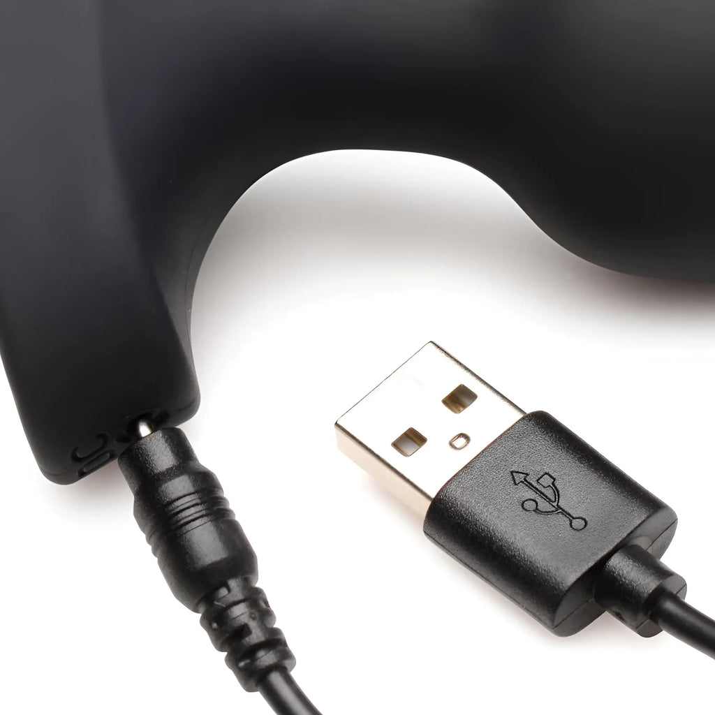 Booty Sparks 28X silicone anal plug, black, shown with a magnetic USB charging cable connected to the base.