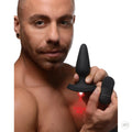 Man holding a black Booty Sparks 28X laser anal plug and remote; the device projects a red "FUCK ME" text.