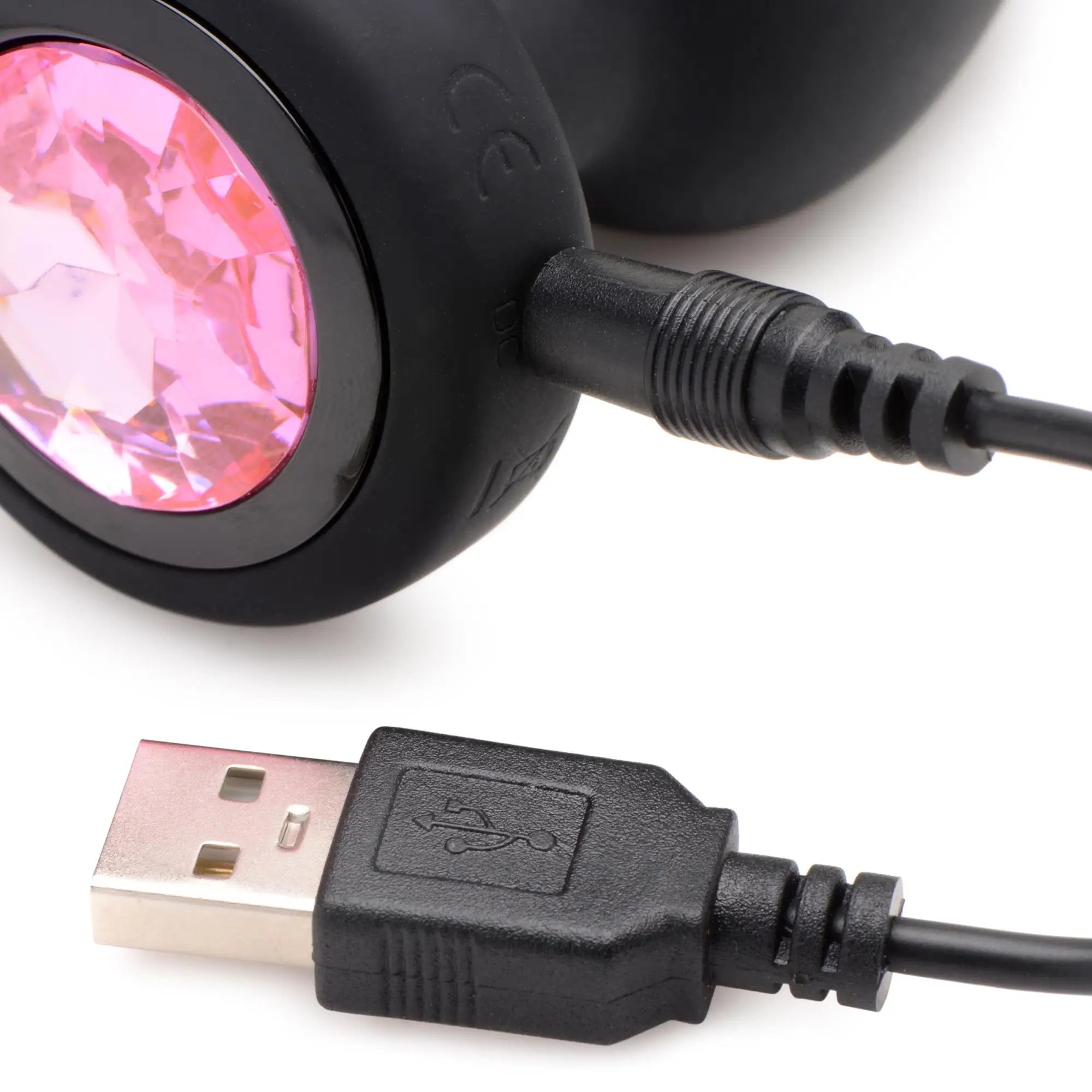 Booty Sparks 28X vibrating black silicone anal plug with a pink jewel base and its black USB charging cable.