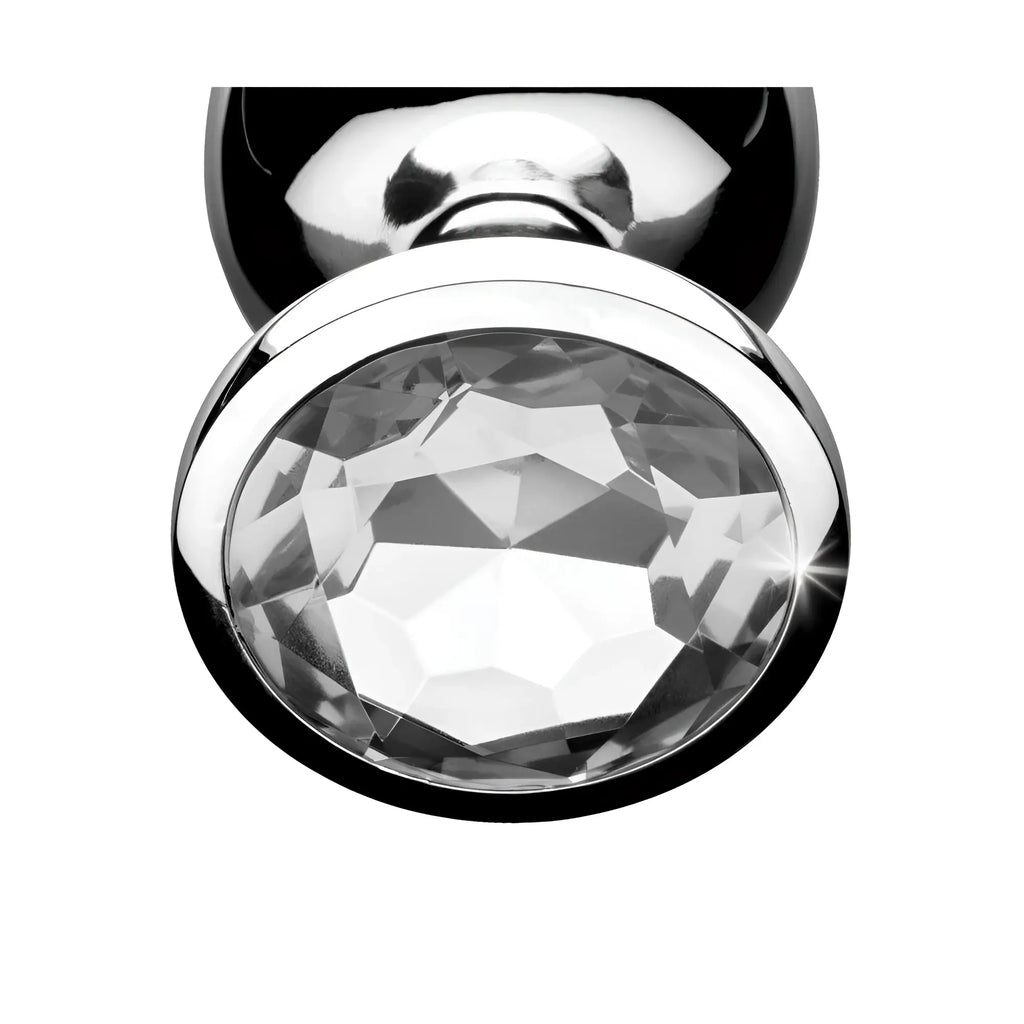 Booty Sparks Clear Gem Anal Plug: A close-up of a silver-toned metal plug base featuring a large, sparkling clear gem.