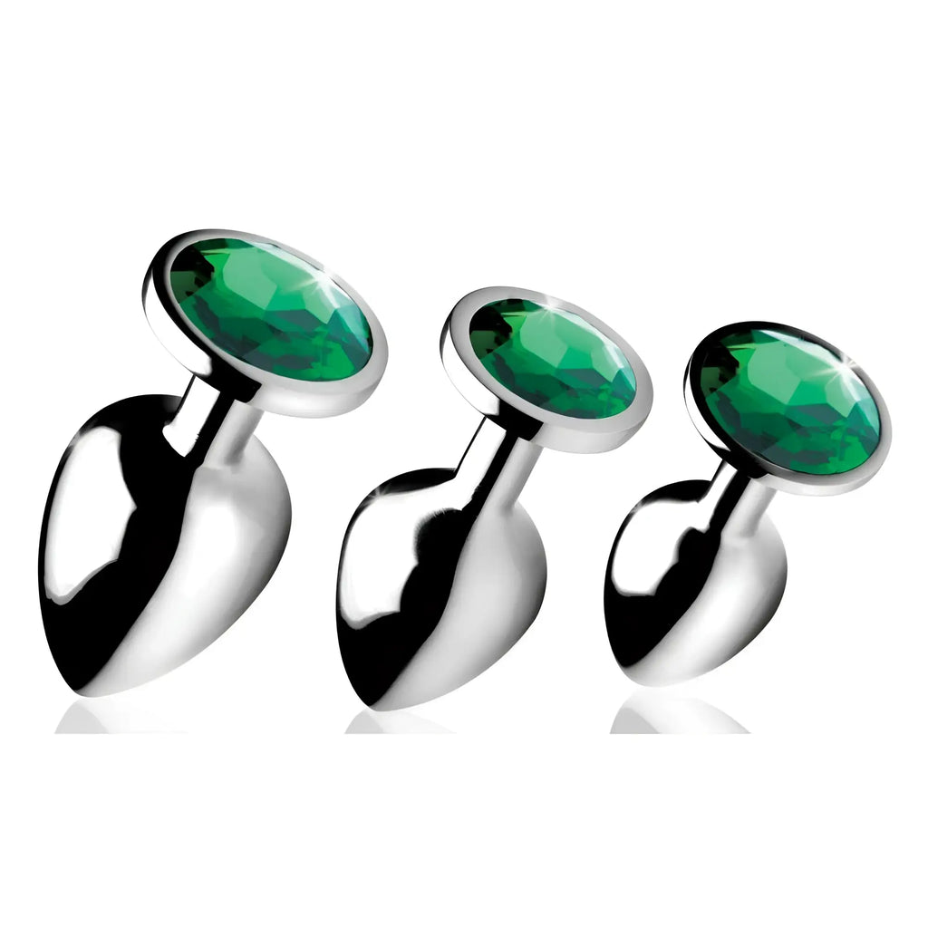 Booty Sparks Emerald Gem anal plug set: three silver metal plugs featuring faceted, round emerald-green crystals.