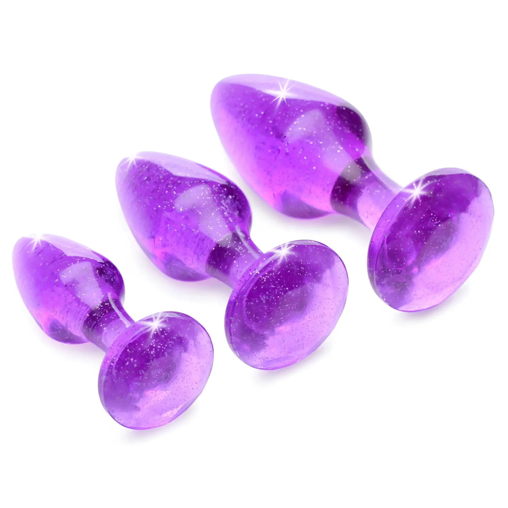 Booty Sparks Glitter Gem Anal Plug Set: three purple, translucent, glitter-filled anal plugs in graduating sizes.