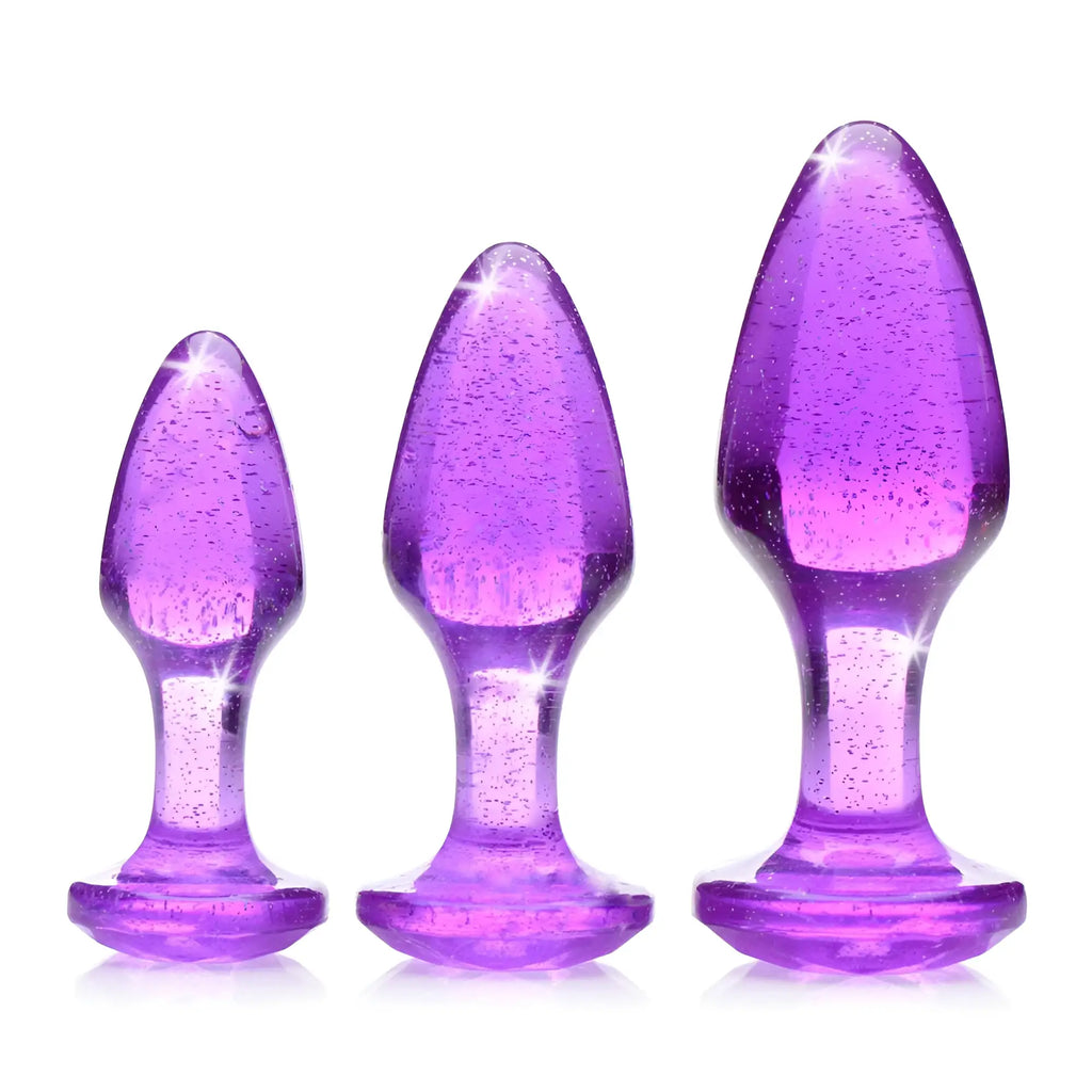 Booty Sparks Glitter Gem anal plug set: three purple, glittery, teardrop-shaped silicone plugs in graduated sizes.