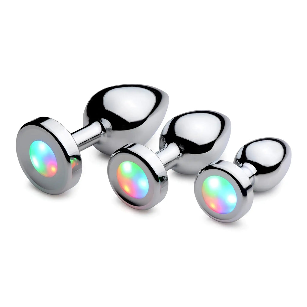 Three chrome-finished Booty Sparks anal plugs with glowing, multi-colored LED bases on a white background.