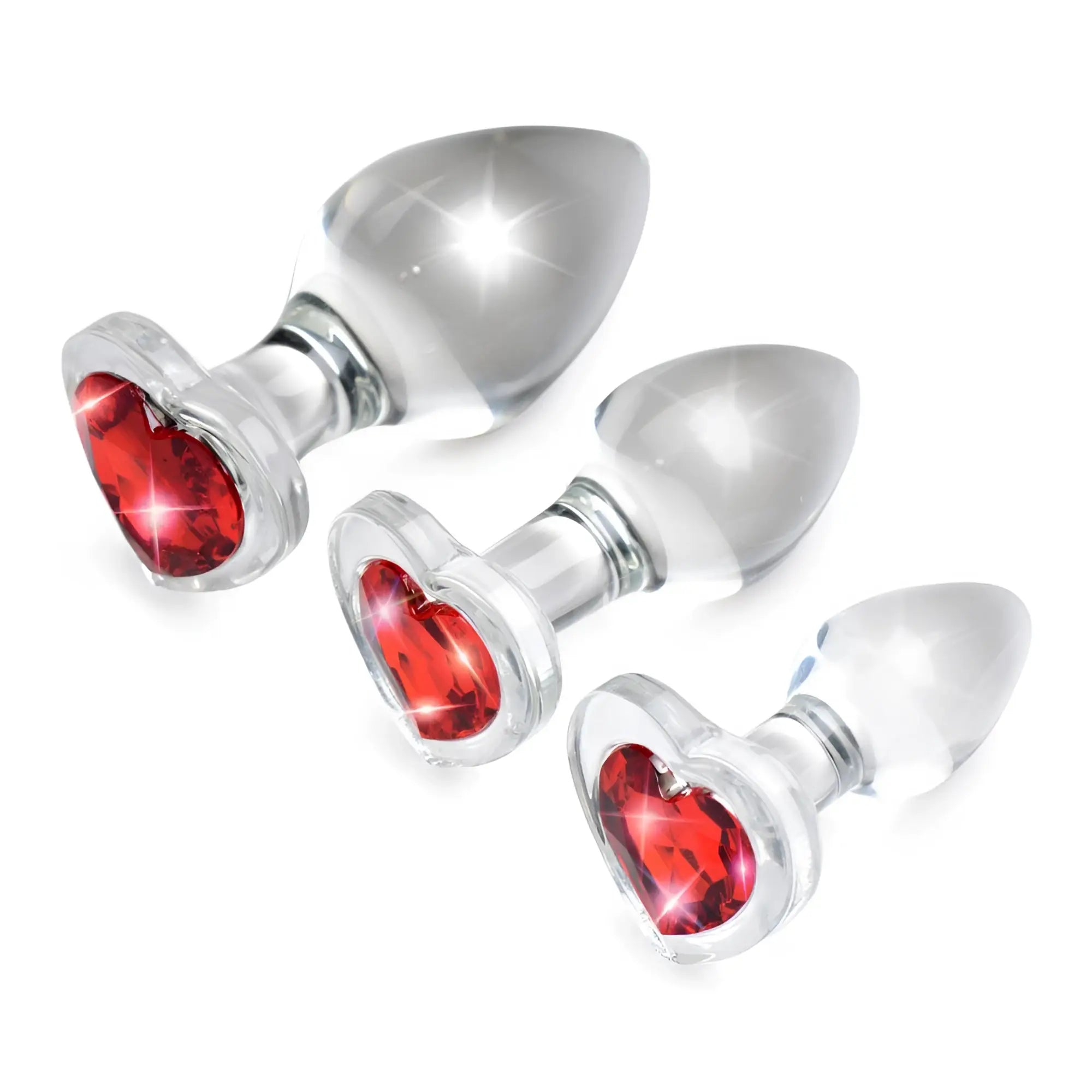 Booty Sparks set: Three clear glass anal plugs in graduated sizes, each featuring a sparkling red heart-shaped gem base.