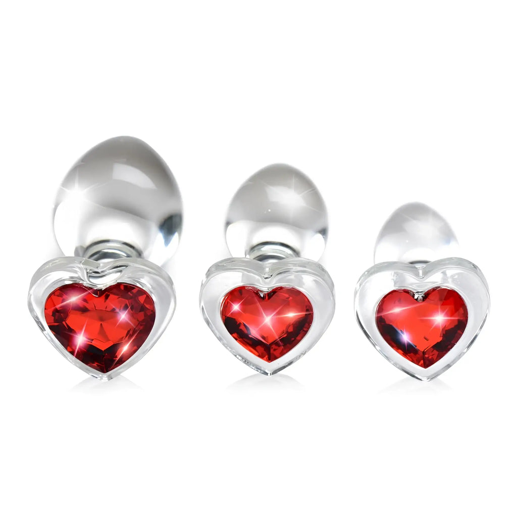 Booty Sparks set: three clear glass anal plugs of varying sizes, each featuring a sparkling red heart-shaped gem base.