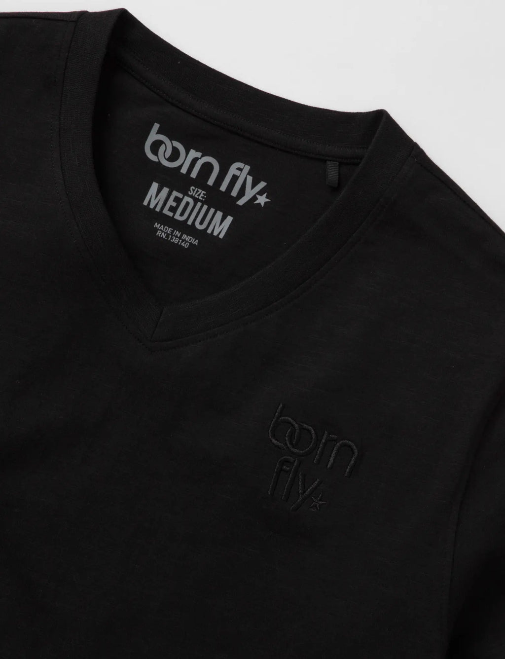 Black cotton born fly v-neck tee with subtle logo embroidery on chest and tagline printed inside the collar