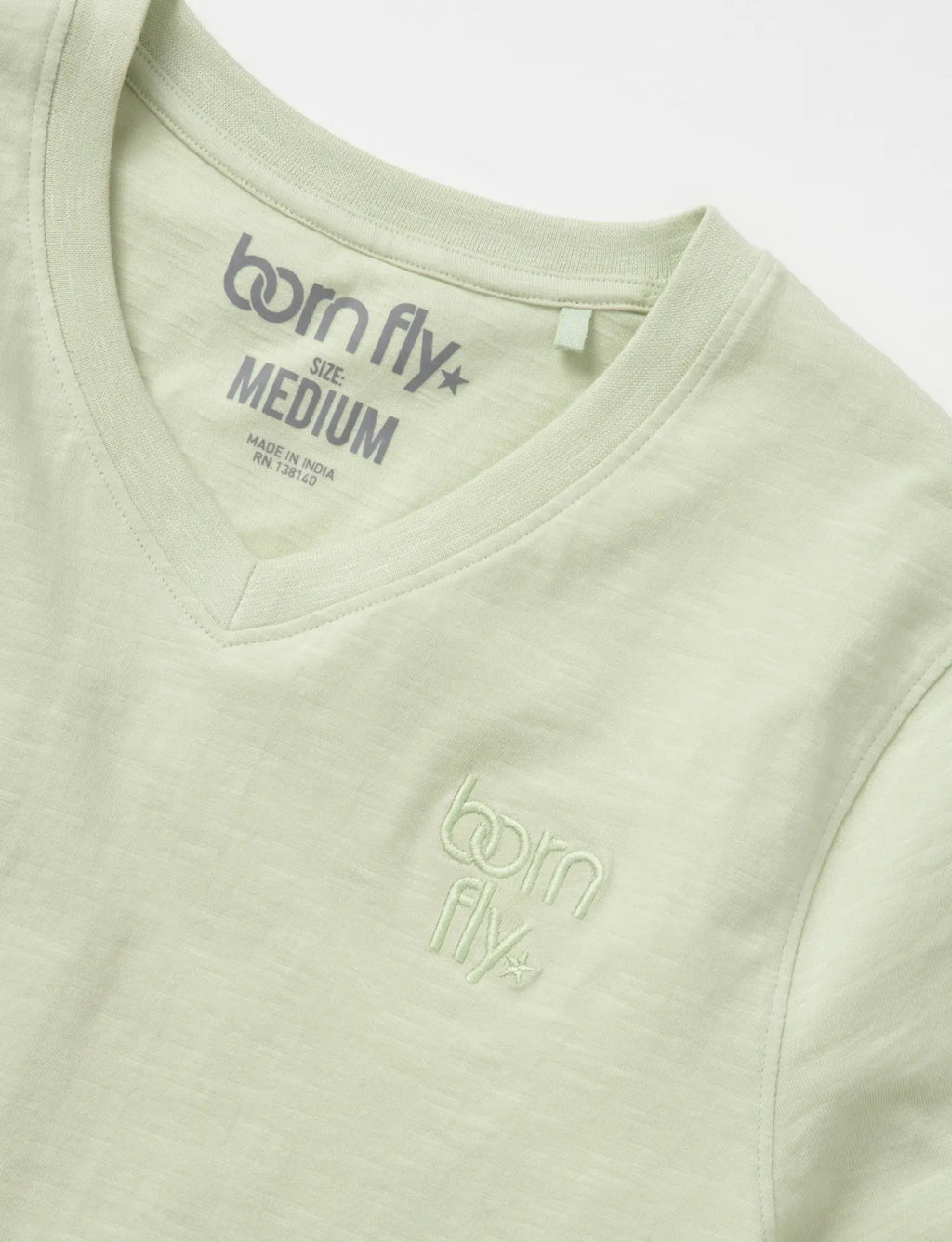 A light green cotton born fly v-neck tee with subtle embroidered logo on the chest and matching collar tag