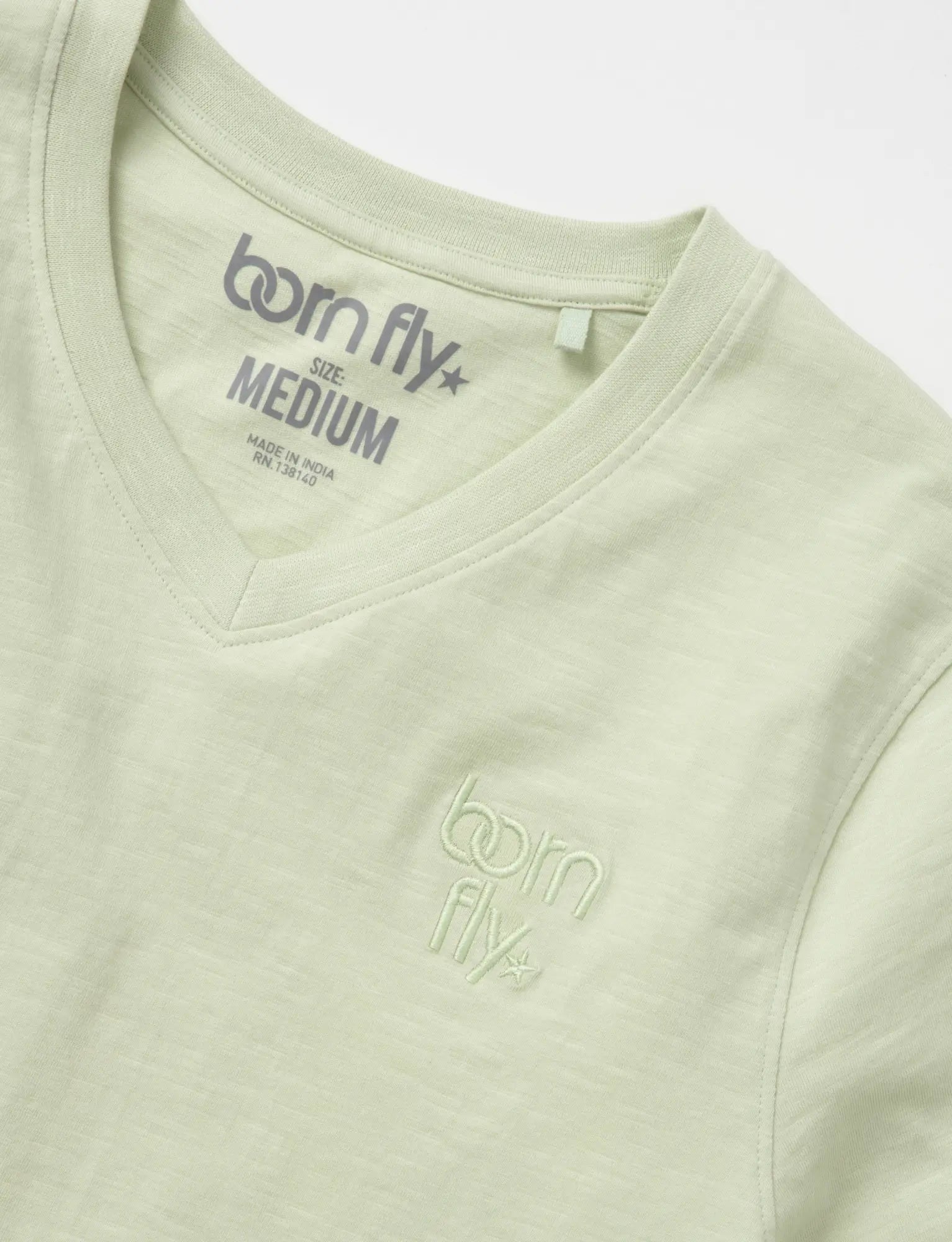 A light green cotton born fly v-neck tee with subtle embroidered logo on the chest and matching collar tag