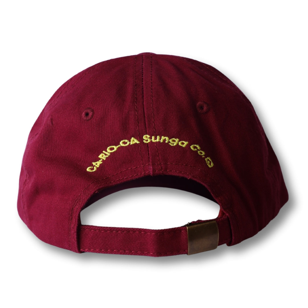 Image of the back side of a maroon cotton dad hat with gold embroidered cario-ca sunga co text from boy from rio flip collection