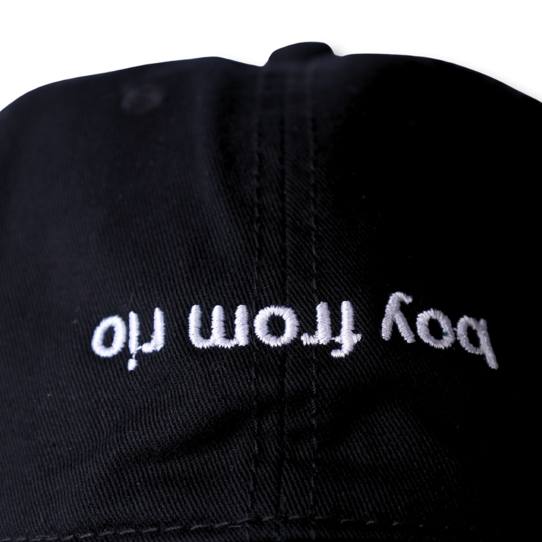 Black dad hat with white embroidered text boy from oil named boy from rio flip in cotton material