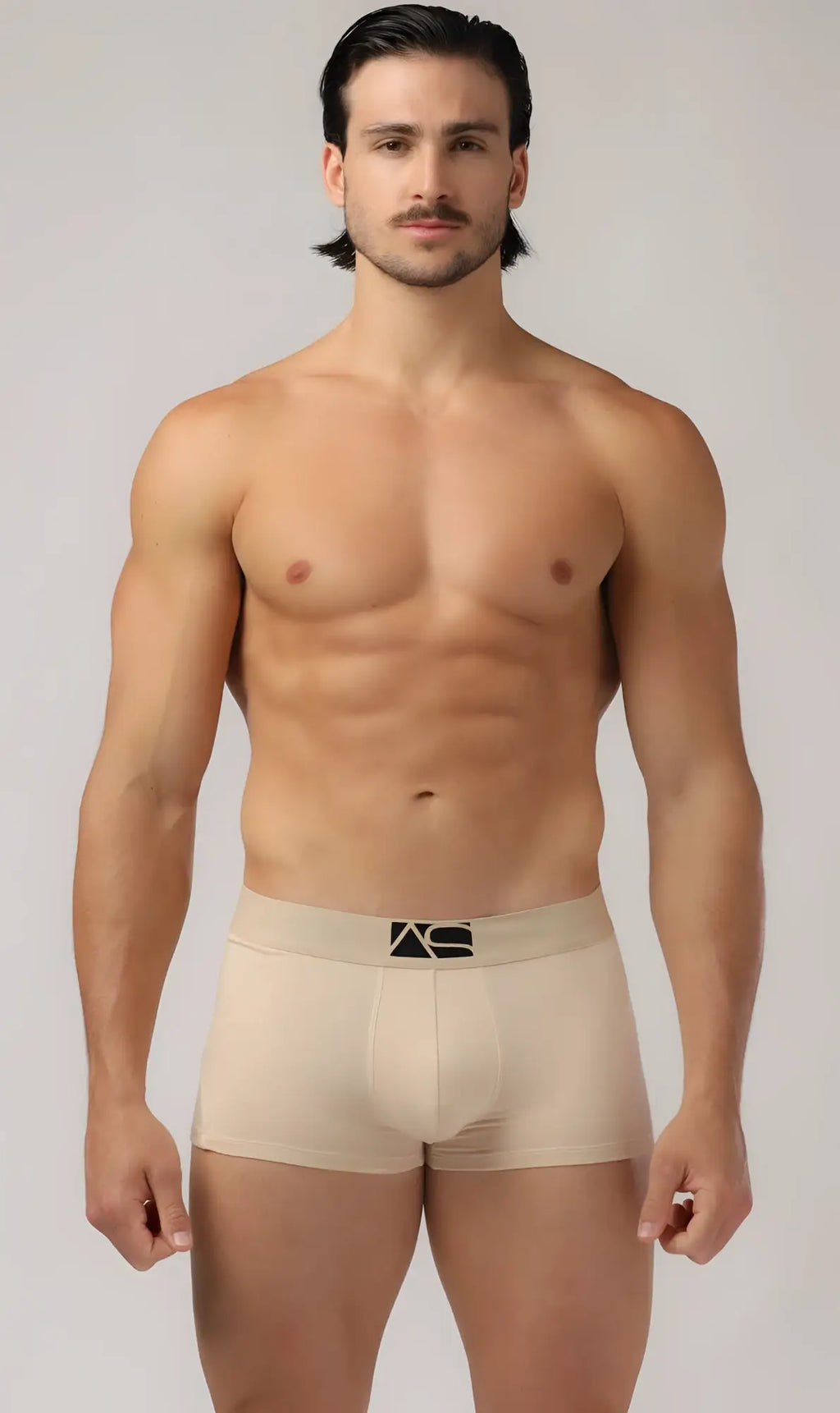 Beige men’s brief trunks with a black logo on the waistband made of soft breathable fabric