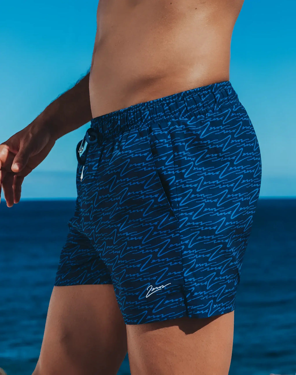 Dark blue byron swim short with light blue abstract wave pattern and white signature logo on lower right leg