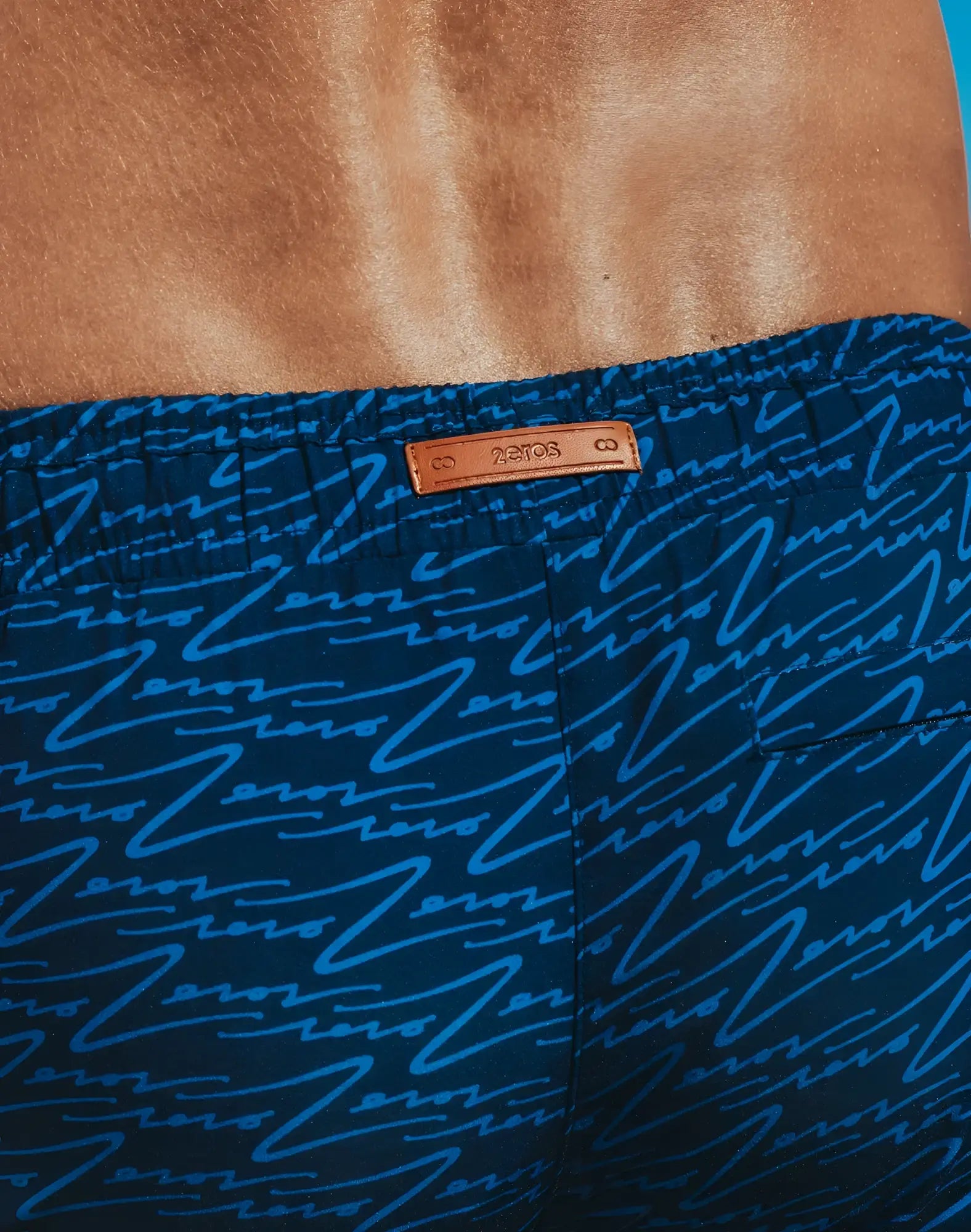 Dark blue Byron swim short with a light blue abstract line pattern and tan leather brand tag for casual swimwear