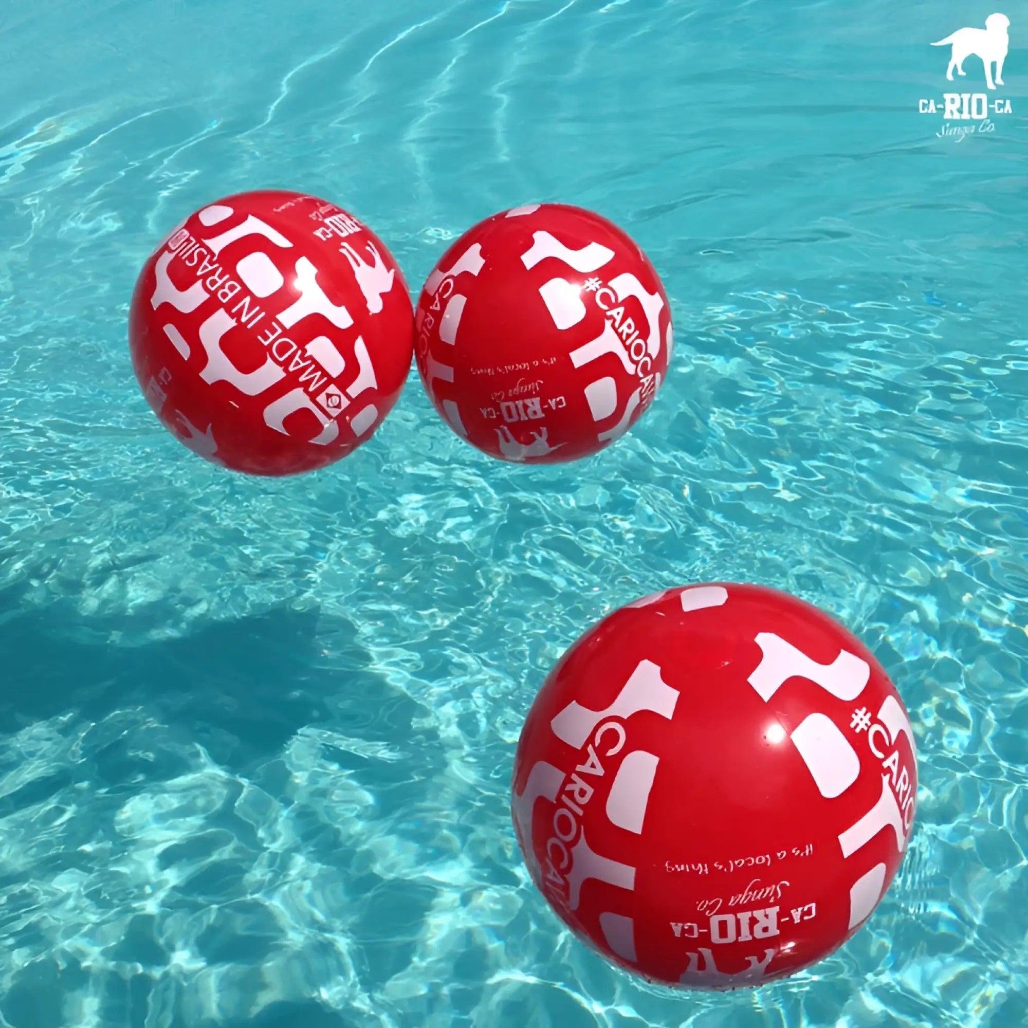 Red inflatable CA-RIO-CA beach ball 24 inch with white text and graphics floating in clear blue water