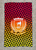 A vibrant red black and yellow gradient brazilian beach towel with an orange shield emblem and white dog silhouette