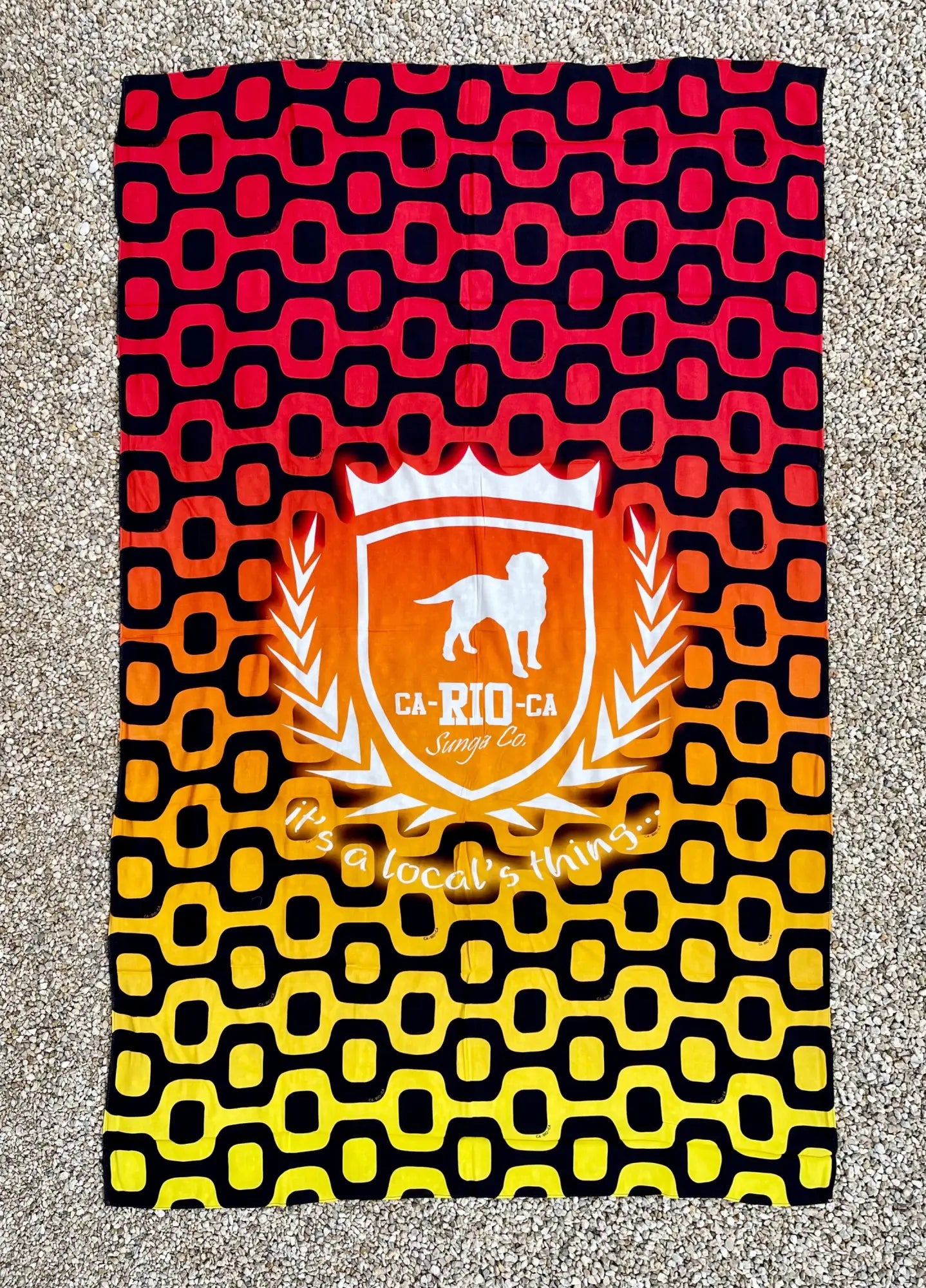 A vibrant red black and yellow gradient brazilian beach towel with an orange shield emblem and white dog silhouette