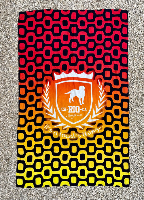 A vibrant red black and yellow gradient brazilian beach towel with an orange shield emblem and white dog silhouette